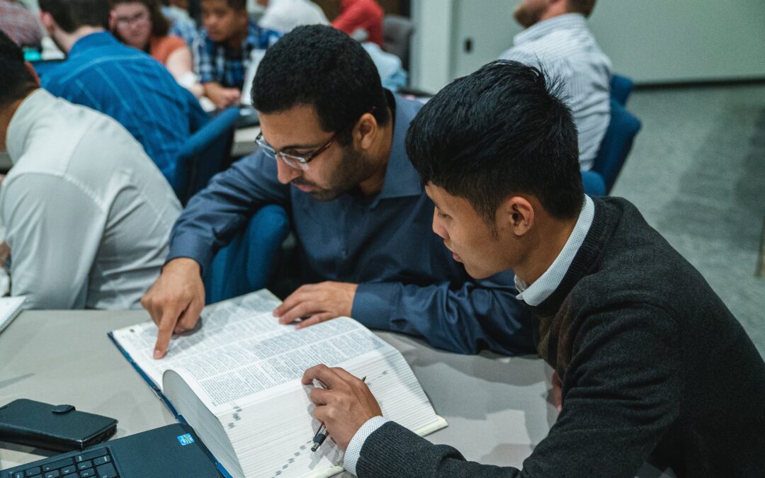 Photo of 2 students studying the Bible during class. Featured image for Spring 2025 enrollment for Bible college.